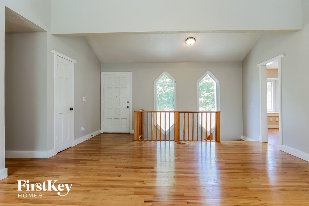 A spacious room with wooden floors and white walls.