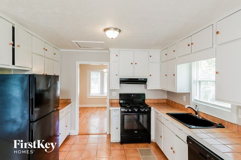 A kitchen with a black fridge and stove top oven.