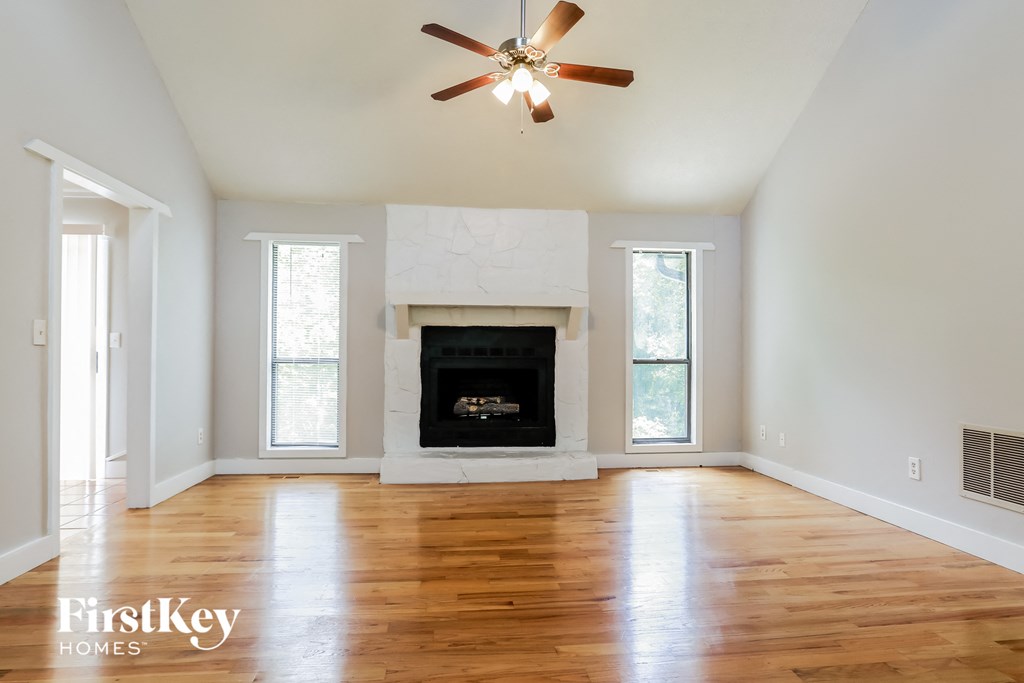 A spacious room with a fireplace and a ceiling fan.