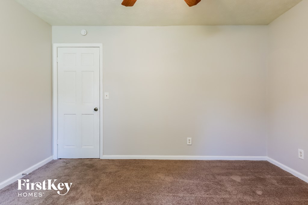 A room with a white door and a brown carpet.