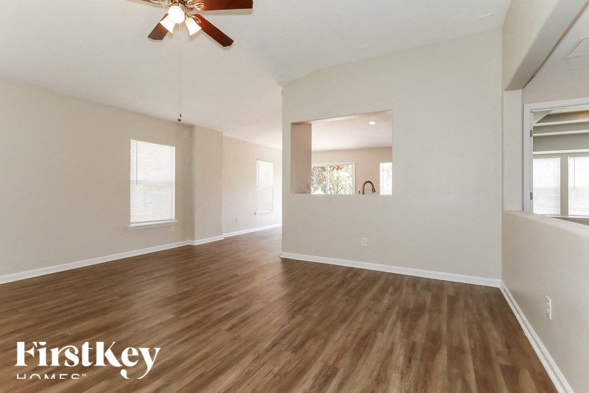 A spacious room with wooden flooring and a ceiling fan.