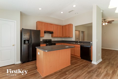 a kitchen with black appliances and wood flooring and wooden cabinets