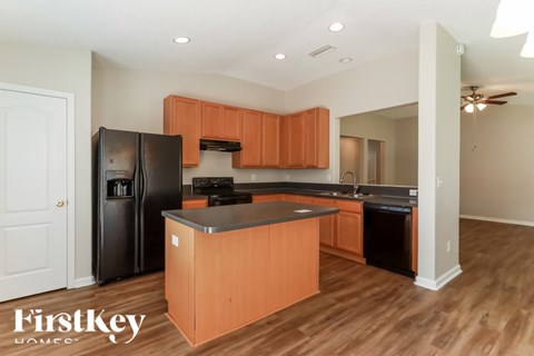 A kitchen with wooden cabinets and a black fridge.