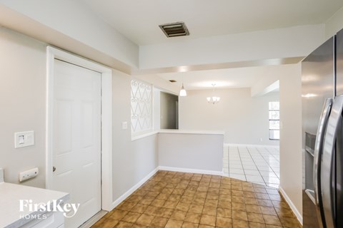 A kitchen area with a tiled floor and a refrigerator on the right.
