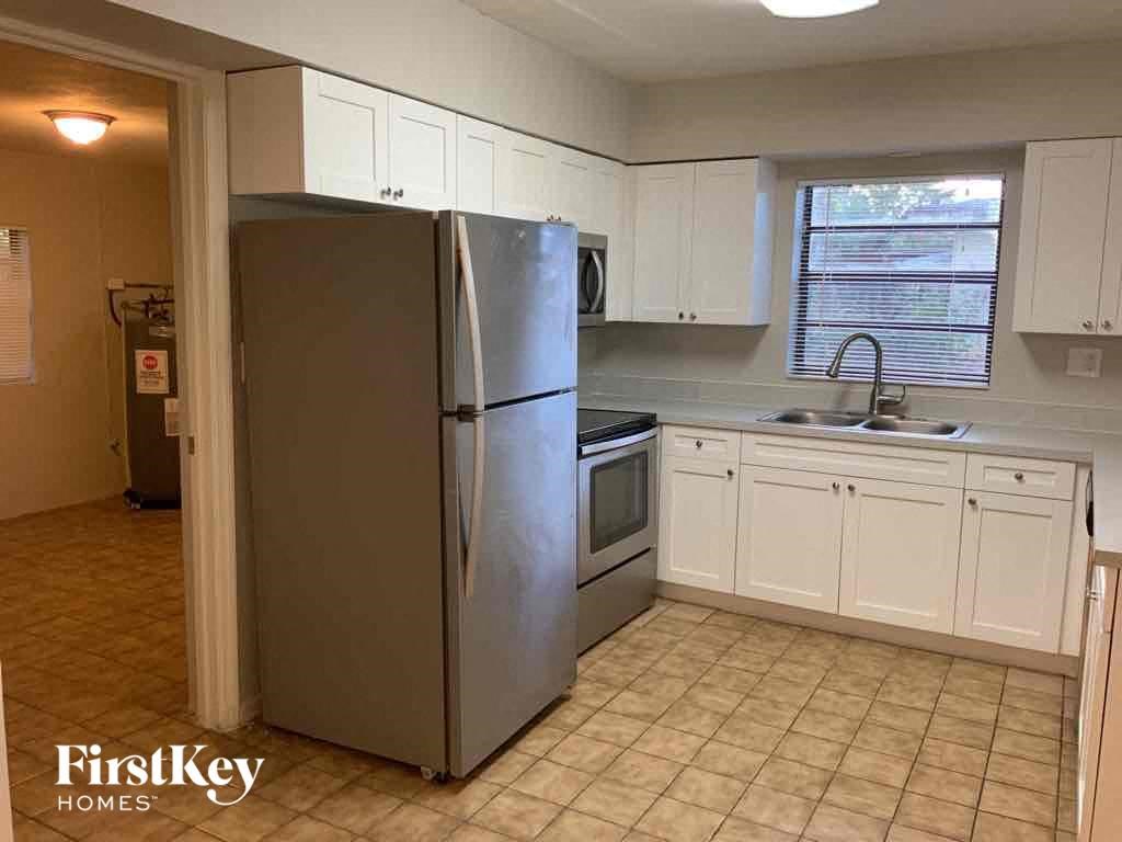 A kitchen with a refrigerator, sink, and cabinets.