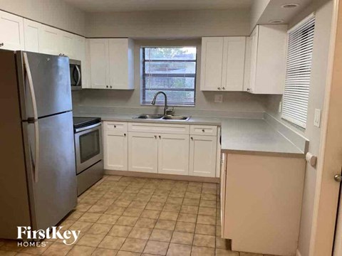 A kitchen with white cabinets and a stainless steel refrigerator.