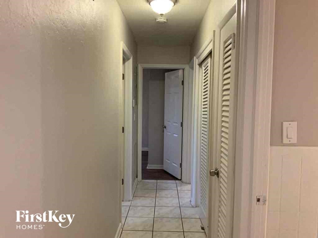 A hallway with a white door and a white wall.