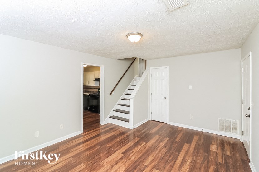 the living room of a house with wood flooring and a staircase
