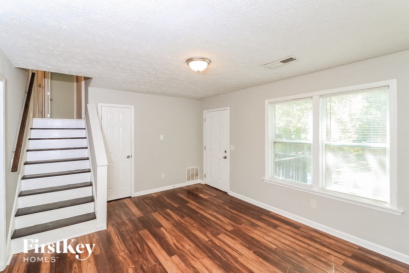 the living room of a house with a staircase and large windows