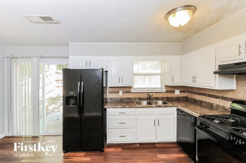 a kitchen with white cabinets and a black refrigerator