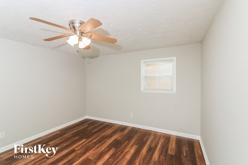 a bedroom with a ceiling fan and wood flooring