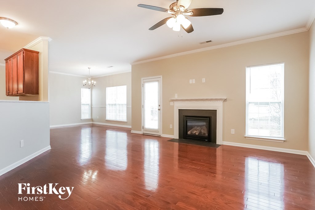 A spacious living room with a fireplace and a ceiling fan.