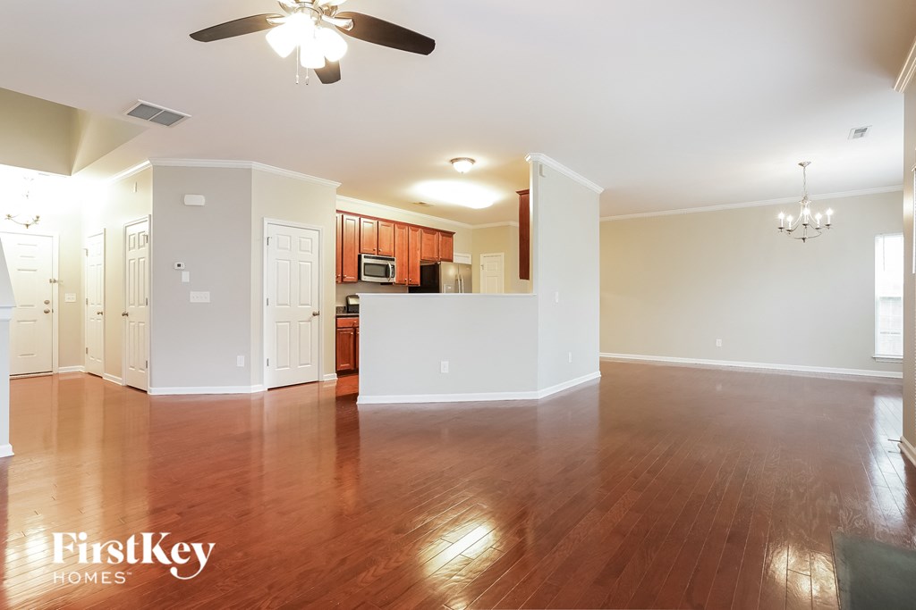 A spacious room with wooden floors and a ceiling fan.