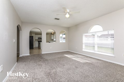 A spacious room with a carpeted floor and a ceiling fan.