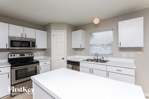 A kitchen with white cabinets and appliances.