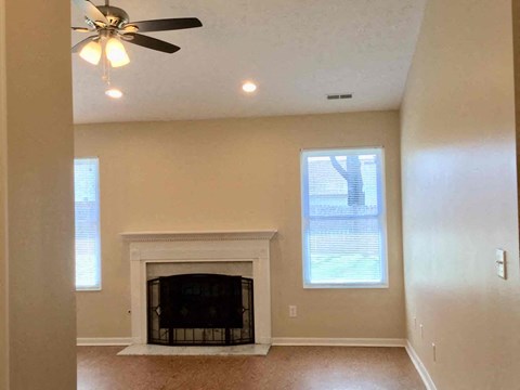a living room with a fireplace and a ceiling fan