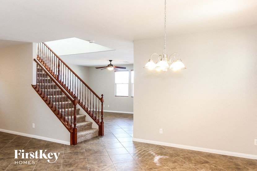 A spacious room with a staircase and a chandelier.