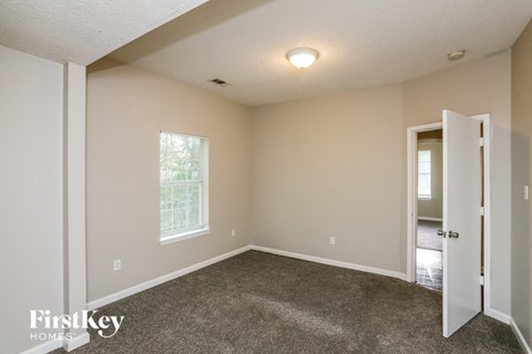the living room of a home with carpet and a door to a hallway