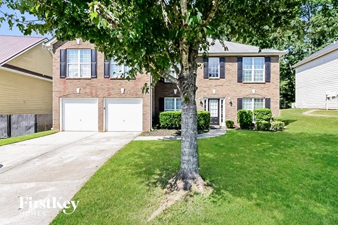 a large brick house with two garage doors and a tree in the front