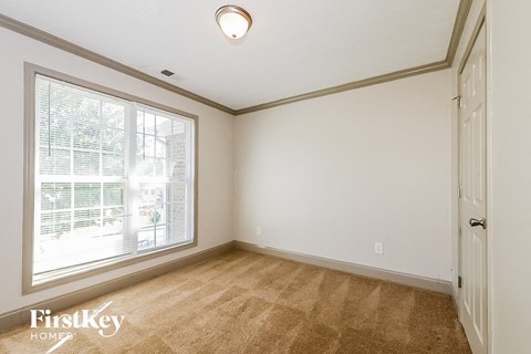 a bedroom with a large window and white walls and carpet