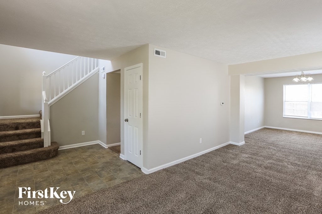 A spacious room with a staircase and a window.