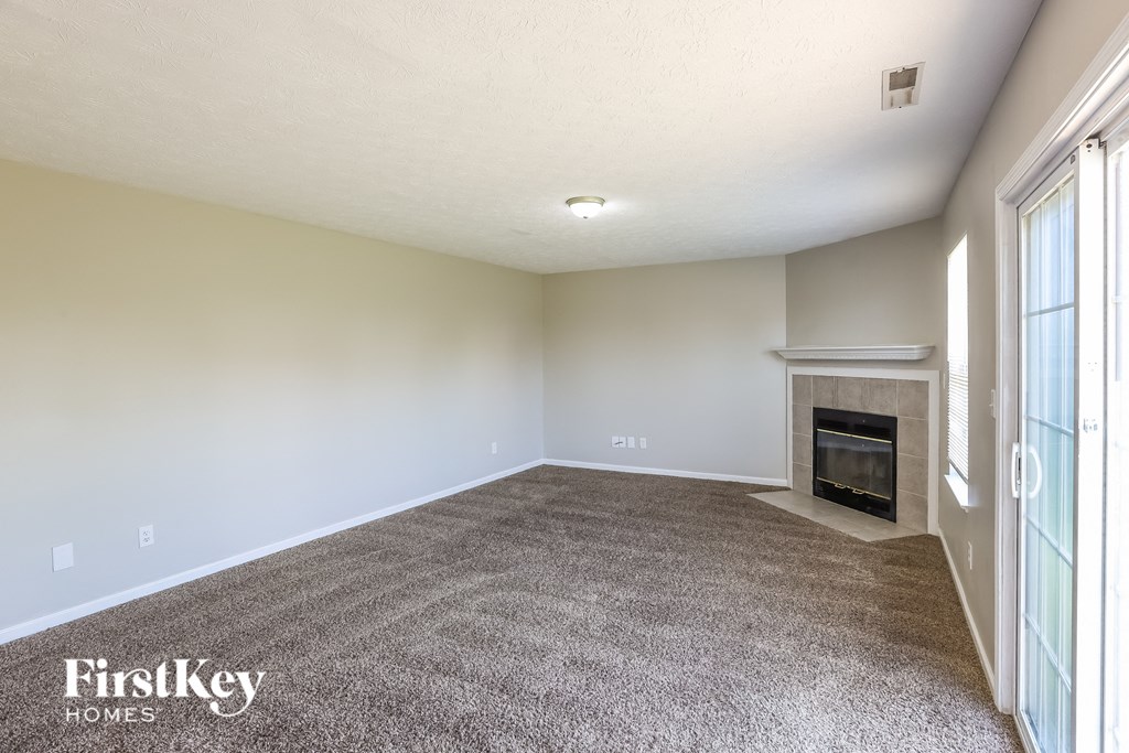 A spacious living room with a fireplace and a carpeted floor.