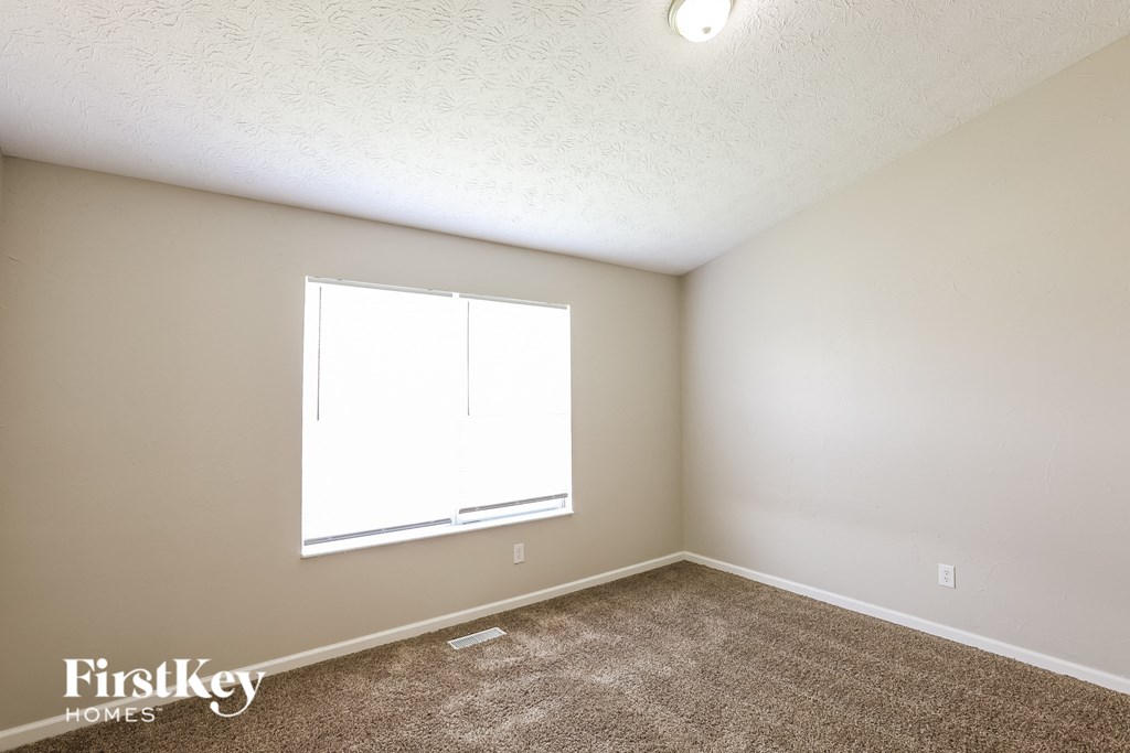 A room with a window and carpeted floor.