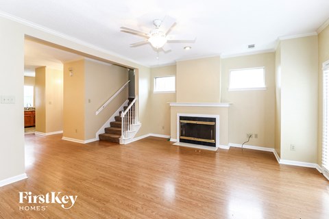 A spacious living room with wood flooring and a fireplace.