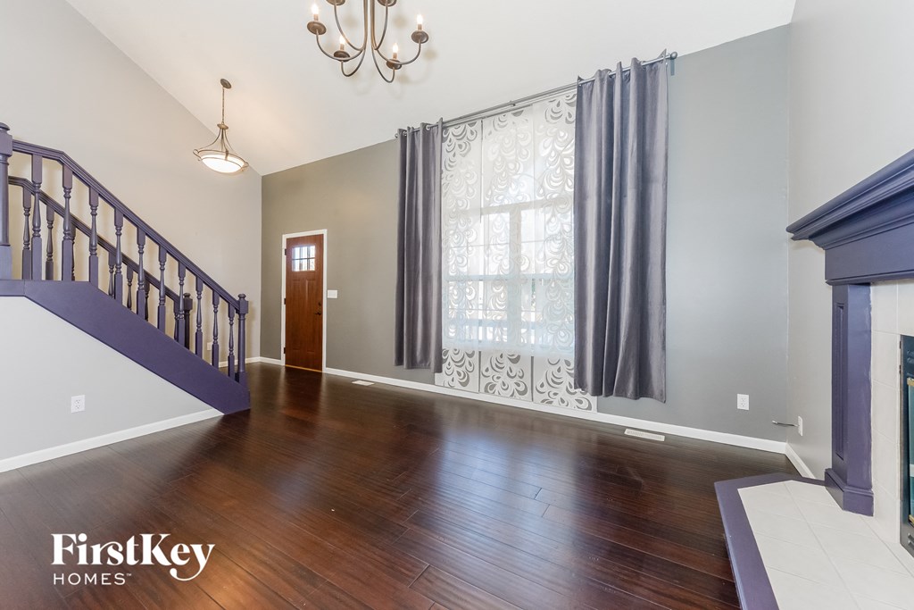 an empty living room with a staircase and a window with curtains