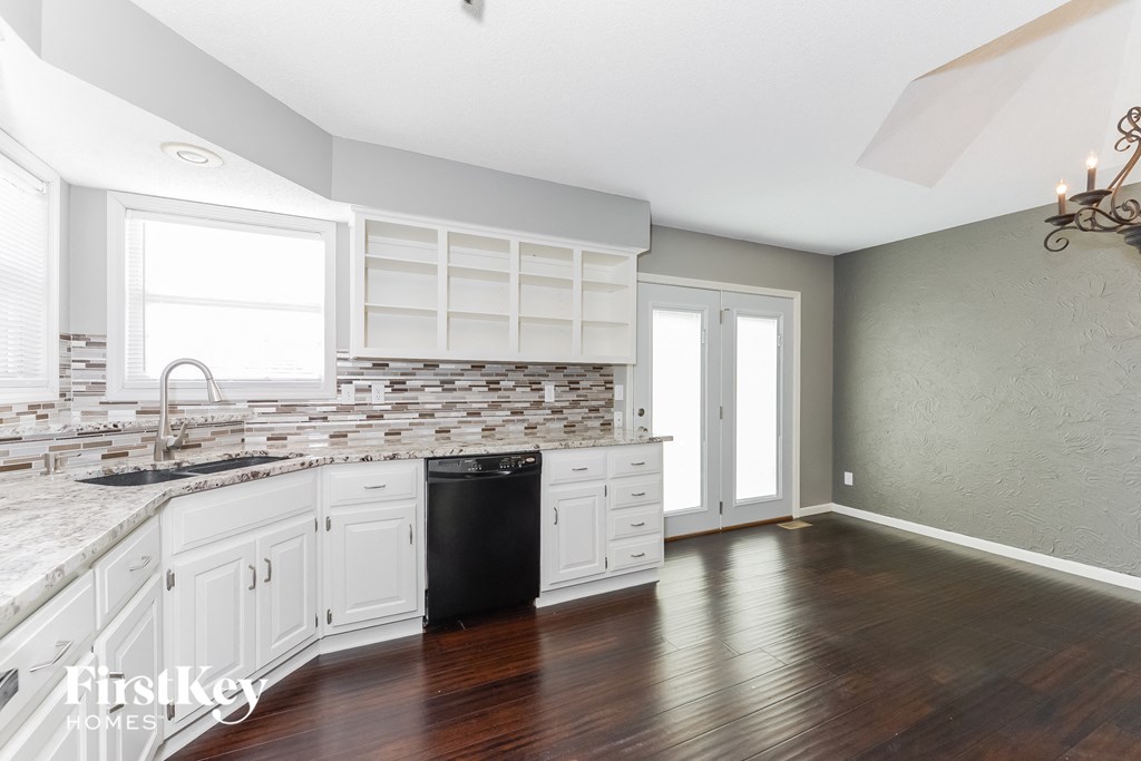 a kitchen with white cabinets and a black dishwasher