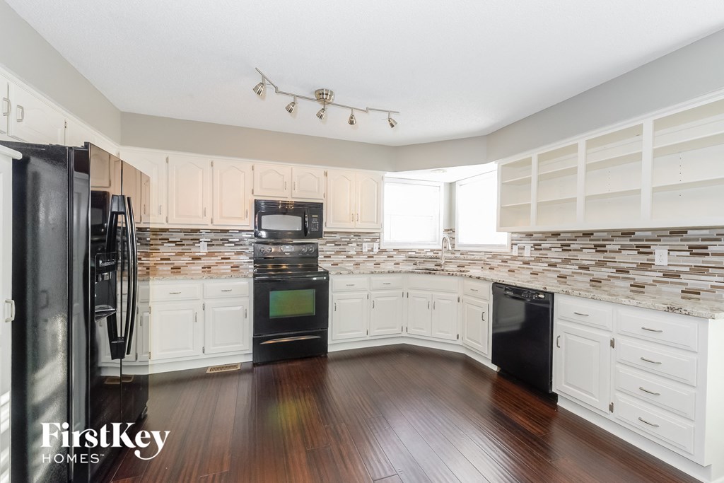 a kitchen with white cabinets and black appliances