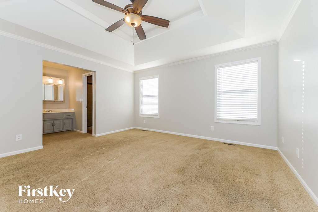 an empty living room with a ceiling fan and a bathroom