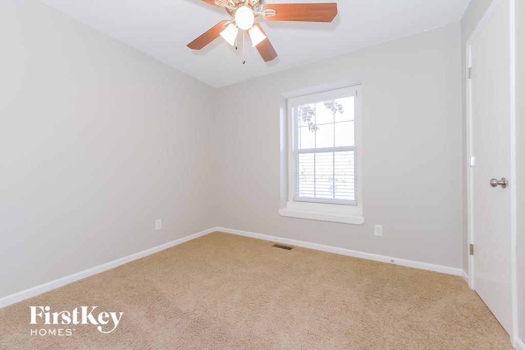 a empty room with a ceiling fan and a window
