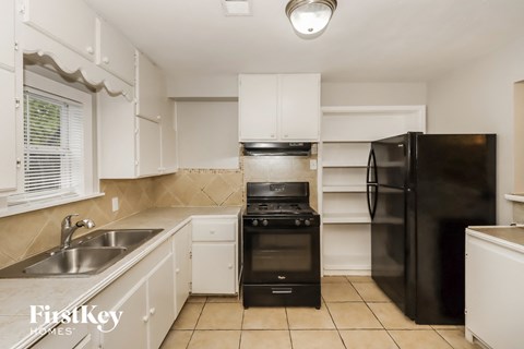 a kitchen with white cabinets and black appliances and a sink