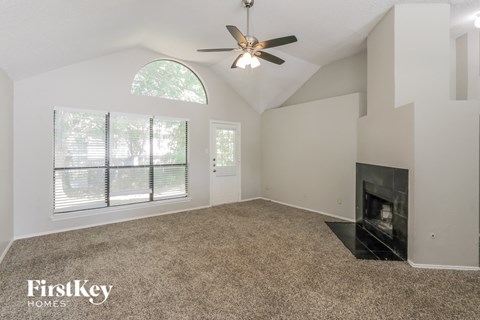 A spacious room with a fireplace and a ceiling fan.