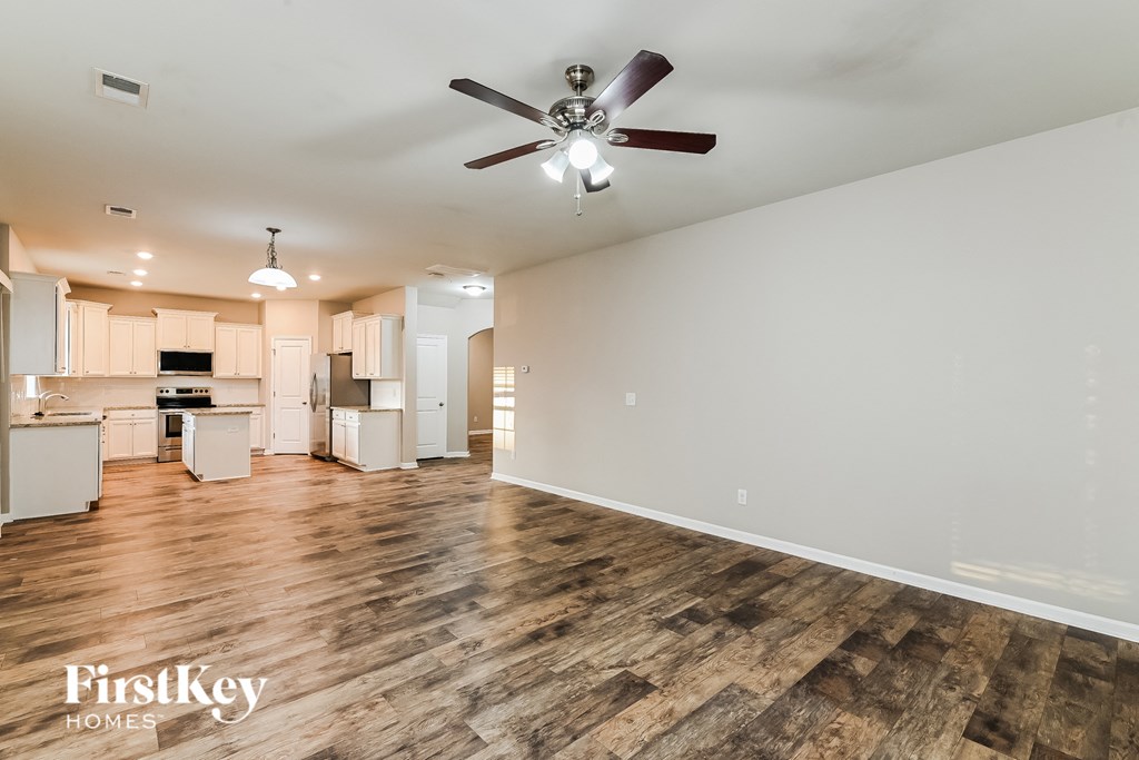 a living room with a ceiling fan and a kitchen