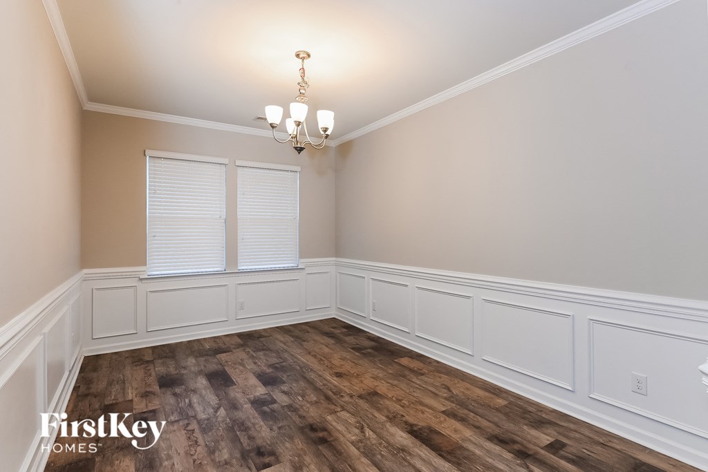 a dining room with white walls and wood flooring and a chandelier