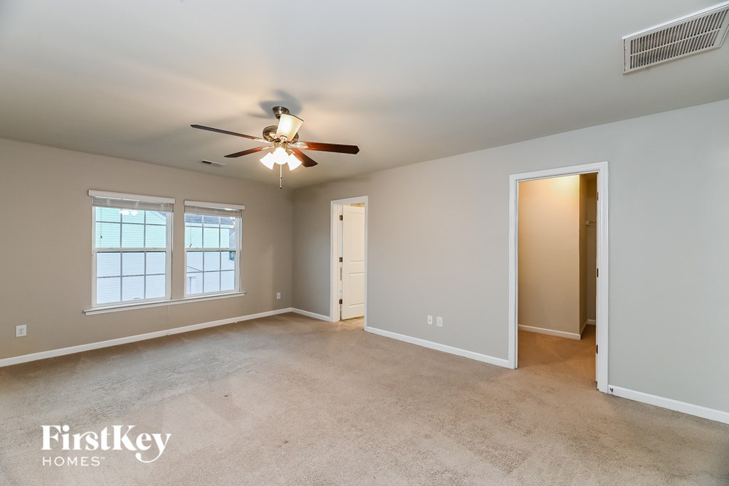 an empty living room with a ceiling fan and a door to a closet