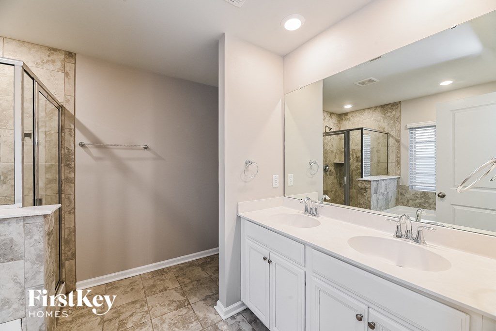 a white bathroom with two sinks and a shower