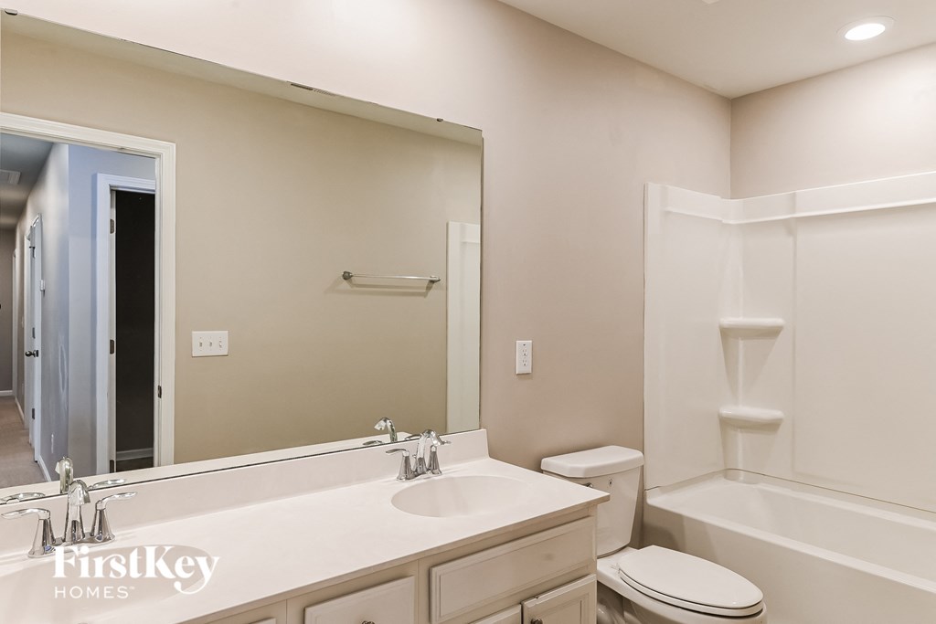 a white bathroom with a large mirror and a white toilet and sink