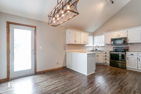 A kitchen with white cabinets and a wooden floor.
