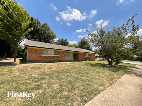 a small brick house with a lawn and trees