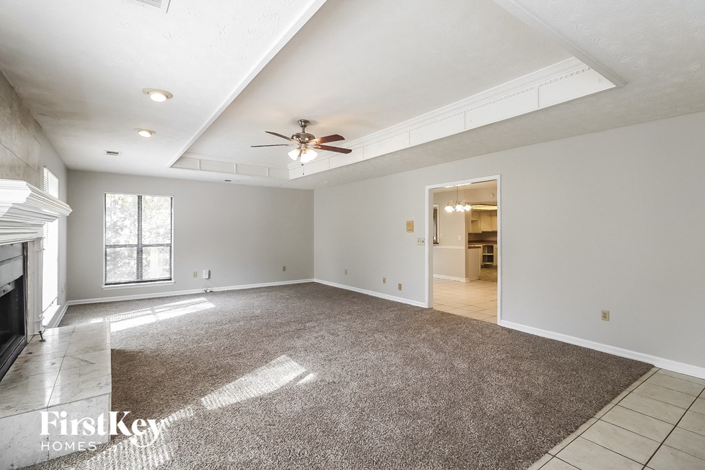 an empty living room with a ceiling fan and a rug