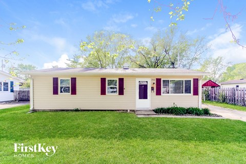 A yellow house with red trim and a red awning is for sale.