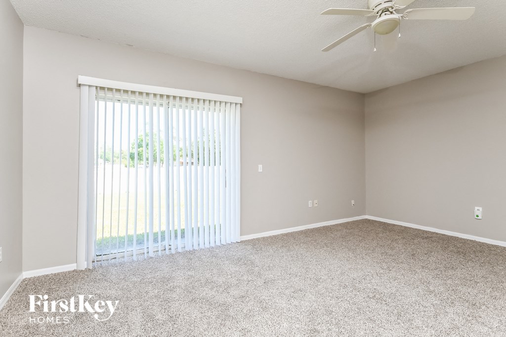 a living room with a large window and a ceiling fan