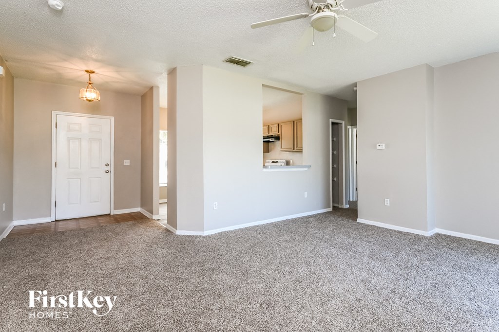a spacious living room with carpet and a ceiling fan