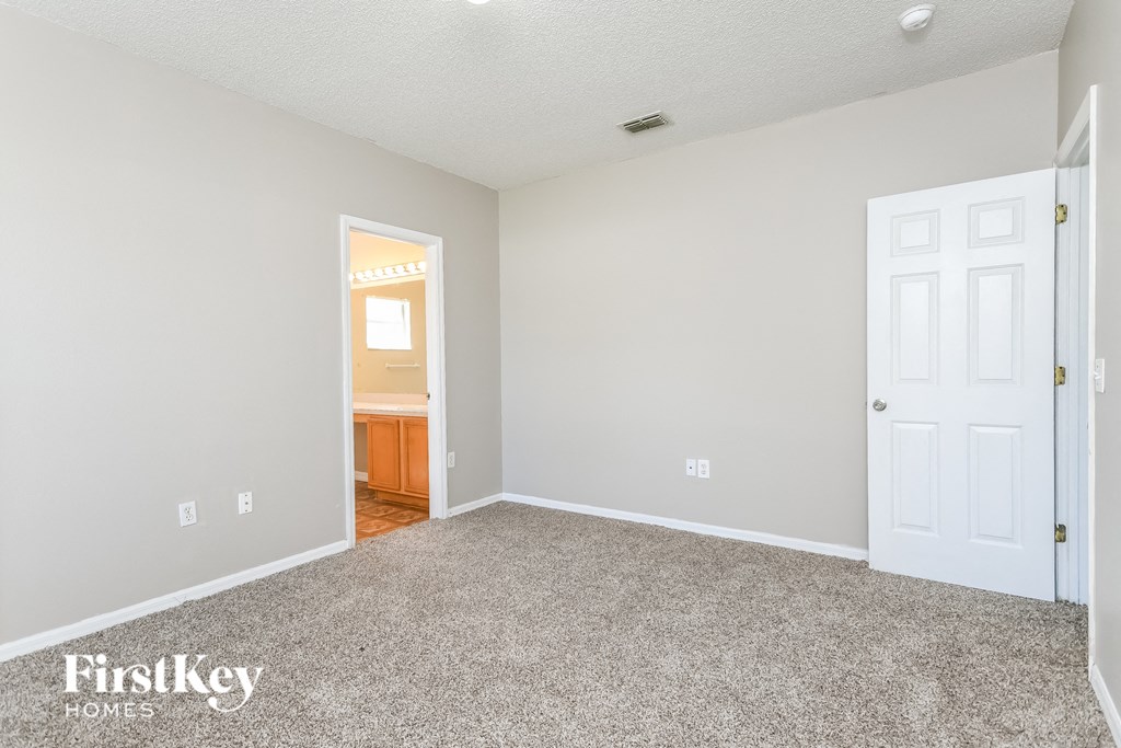 a bedroom with carpet and a door to a bathroom