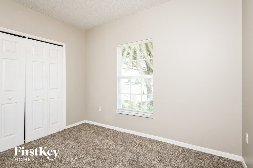 a bedroom with carpet and a window and two closets