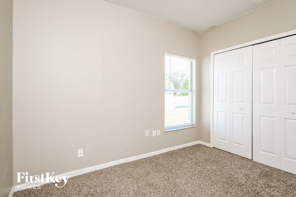 a bedroom with carpet and two closets and a window
