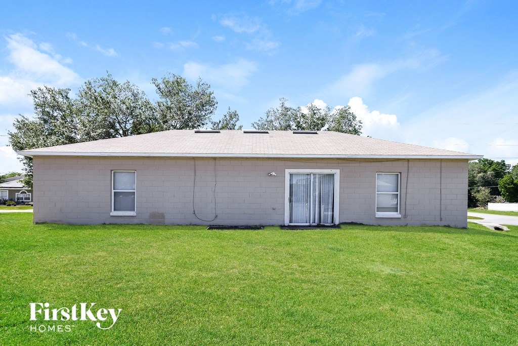 a small white brick house with a grassy yard